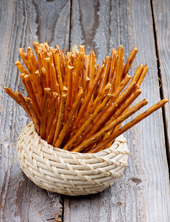Bunch of Pretzel Rods Sticks in Wicker Bowl isolated on Rustic Wooden background