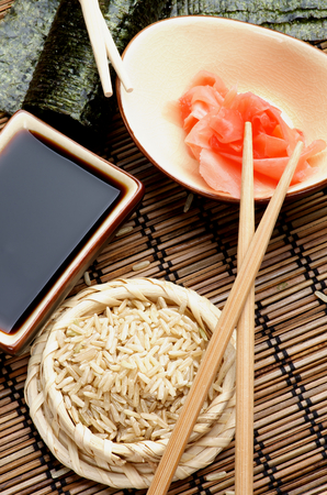 Ingredients to Preparing Sushi  with Nori, Ginger, Rice, Soy Sauce and Chopsticks on Bamboo Straw Mat. Top Viewの写真素材