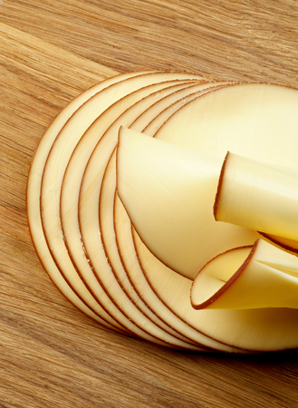 Stack of Sliced Delicious Smoked Cheese isolated on Wooden Cutting Boardの写真素材