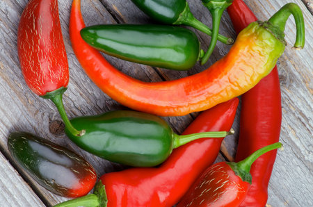 Heap of Red and Green Habanero and Jalapeño Chili Peppers isolated on Rustic Wooden background. Top...