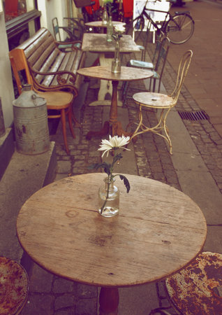 Empty Sidewalk Cafe with Wooden Tables and Old Chairs on Cobblestone Street in Copenhagen Outdoorsの写真素材