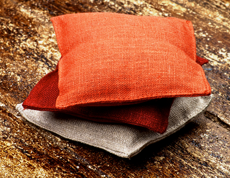 Stack of Three Textile Sachet Pillows closeup on Textured Wooden backgroundの写真素材