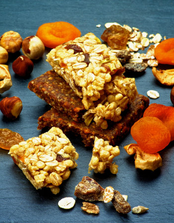 Stack of Useful Granola Bars with Muesli, Nuts, Seed, Raisins and Dried Apricots closeup on Black Stone backgroundの写真素材