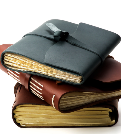 Stack of Various Luxury Handmade Leather Notepads with Craft Paper Cross Section on White backgroundの写真素材