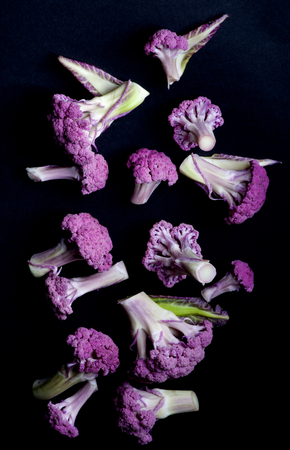 Arrangement of Fresh Raw Purple Sprouts of Cauliflower with Leafs isolated on Black background. Top Viewの写真素材