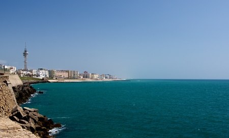 Sea on Modern Town District and Playa De La Cortadura in Sunny Day against Blue Sky Outdoors. Cadiz, Spainの写真素材
