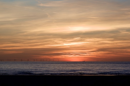 Beautiful Sunset on Dramatic Red Sky with Silhouette of Electric Windmills and Large Sea Liner Outdoors. North Sea, IJmuiderslag, Netherlandsの写真素材