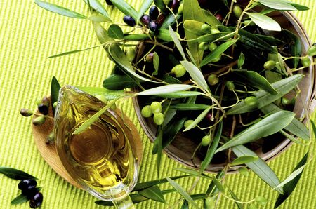 Raw Green and Black Olives with Leafs and Olive Oil in Glass Gravy closeup on Green Textile background. Topの写真素材