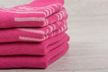 Pile of pink woolen socks on white wooden backgroundの写真素材