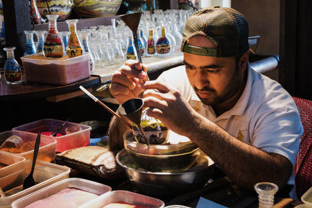 DUBAI, UNITED ARAB EMIRATES - DECEMBER 7, 2016: Craftsman makes souvenirs in a bottle using colored sand.のeditorial素材