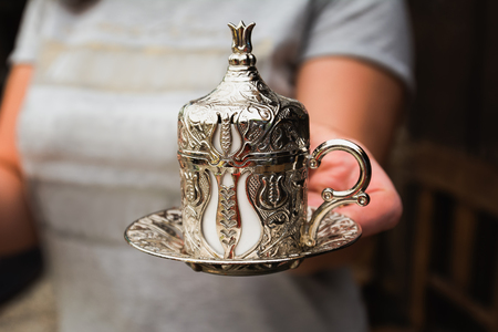 Woman is serving Turkish coffee in a traditional silver cup.の写真素材