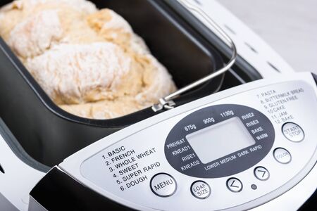 Homemade white flour bread baked in bread maker with digital display.の写真素材