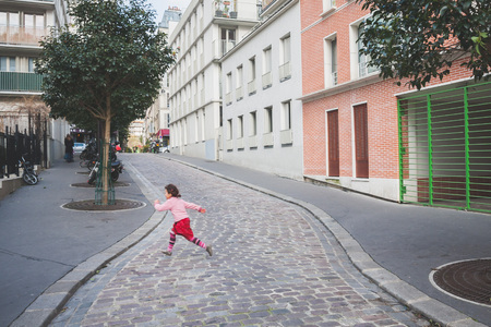 France, Paris - Spring 2008: A little girl in a pink sweater runs across the road. Paris. France.のeditorial素材