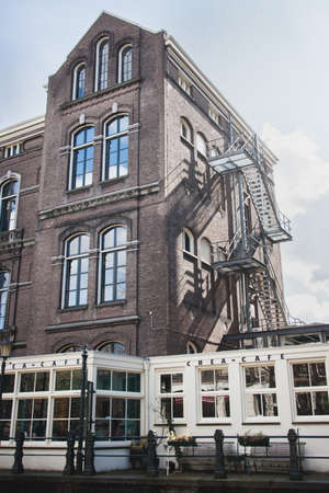 Amsterdam. Netherlands - 06.04.2008. A man with a parrot on his shoulder swims by boat on the canal. One of the buildings of the University of Amsterdam. Netherlandsのeditorial素材