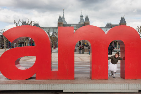 Amsterdam. Netherlands - 06.04.2008. A word Amsterdam from big letters and playing girl.のeditorial素材