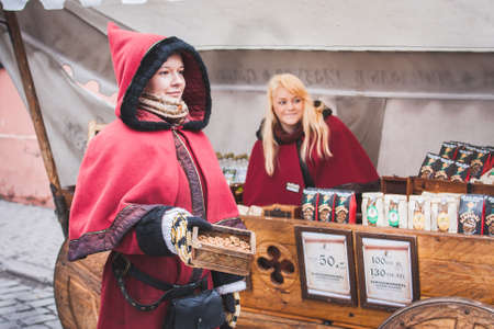 Tallinn, Estonia - April 2010: Girls in national costumes sell sweet fried almonds on the street.のeditorial素材