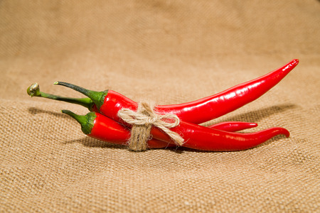 Three Chile peppers tied with a rope  on old clothの写真素材