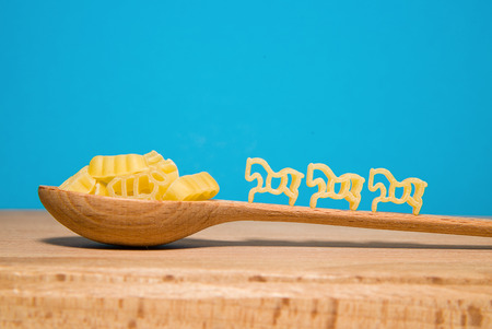 Pasta in the form of animals and a wooden spoon on a blue backgroundの写真素材