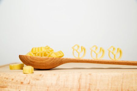 Pasta in the form of animals and a wooden spoon on a white backgroundの写真素材