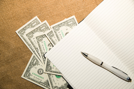 Opened notebook with a blank sheet, pen and money on the old tissueの写真素材