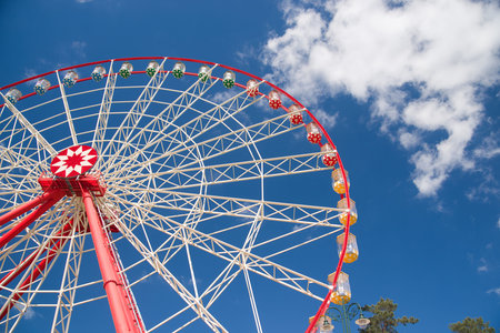 Atraktsion Ferris wheel against a blue sky with cloudsの写真素材