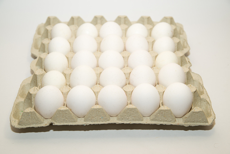 Chicken egg in the package on over whiteの写真素材