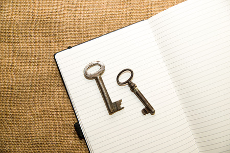 Opened notebook with a blank sheet and keys  on the old tissueの写真素材