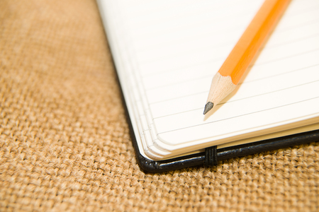 Opened notebook with a blank sheet and pencil on the old tissueの写真素材