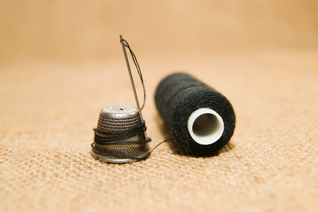 Sewing Needle, thimble and thread spool on the old clothの写真素材