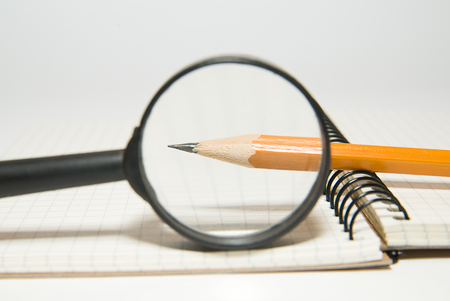 Notepad, pencil and magnifying glass on over whiteの写真素材