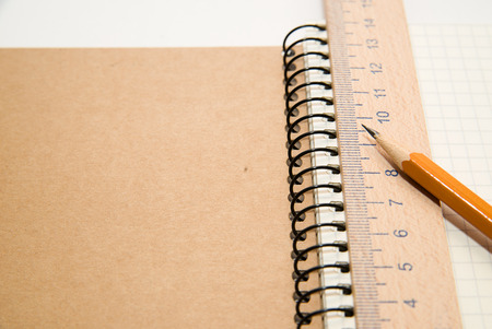 Opened notebook with a blank sheet, pencil and wooden ruler on over whiteの写真素材