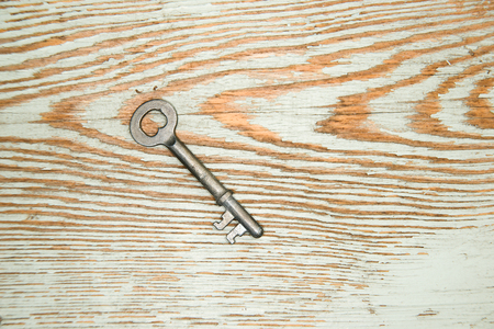 Vintage key from the lock on a wooden textureの写真素材