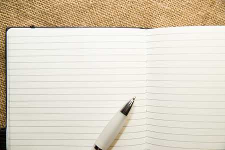 Opened notebook with a blank sheet and pen on the old tissueの写真素材