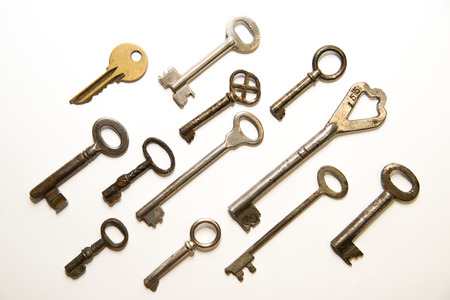 Many vintage keys to the safe on a white backgroundの写真素材