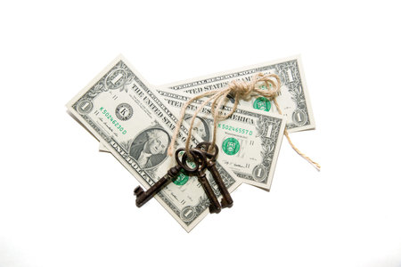 Keys tied with a rope and a few  dollars banknotes on a white backgroundの写真素材
