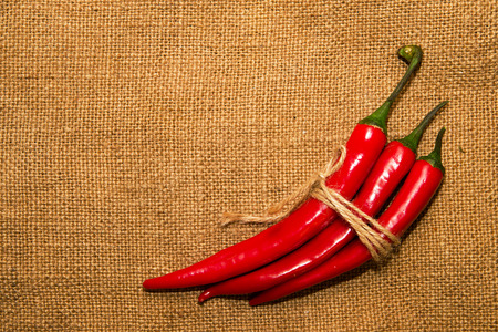 Three Chile peppers tied with a rope  on old clothの写真素材