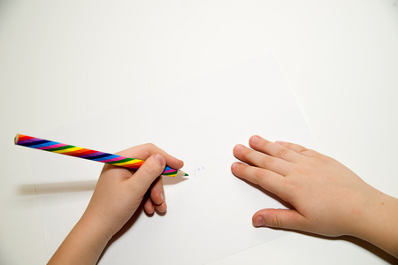 Kid's left hand holding a pencil on a whiteの写真素材