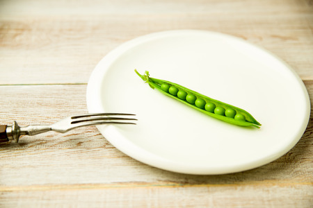 Opened green pea pod on the white plate.の写真素材