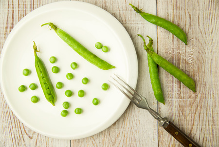 Opened green pea pods on the white plate.の写真素材