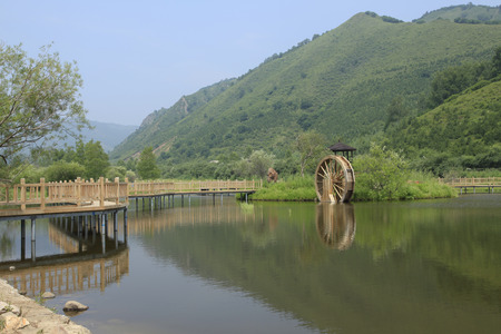 The reservoir in the mountains, has a wood water wheel, is very beautifulの写真素材