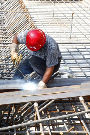 The welding worker in the construction site making reinforcement metal framework for concrete pouringの写真素材