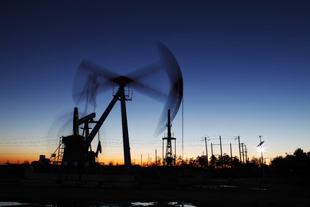 Oil field scene, the evening of beam pumping unit in silhouetteの写真素材