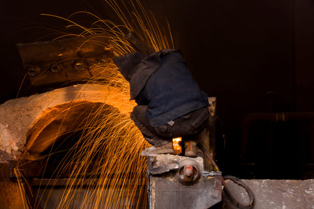 The workshop welder cuts metal, forming an orange spark