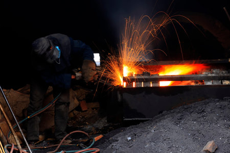 The workshop welder cuts metal, forming an orange spark