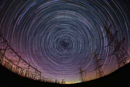 The high-voltage tower and the star track at nightの写真素材