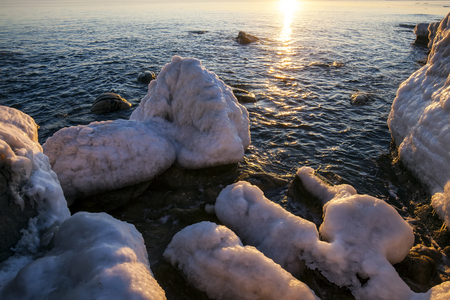 Sunrise by the sea in winter.The rocks were covered with snow and iceの写真素材