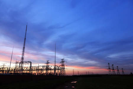 Silhouettes of pylons, substations and high-voltage pylons in the eveningの写真素材