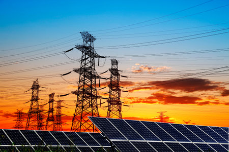 Silhouettes of substations and solar panels. Solar panels and high voltage towers in the evening