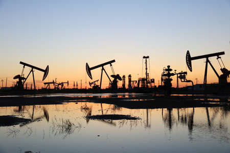 Oil field site, in the evening, oil pumps are running, Silhouette of beam pumping unitの写真素材