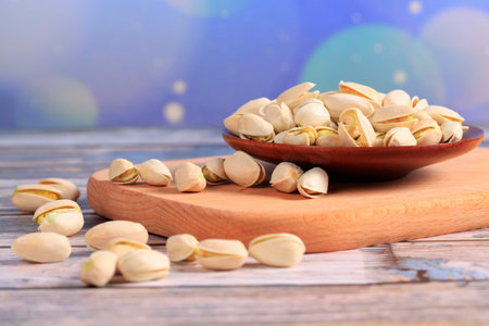 The pistachios are on the wooden board, A close-up
